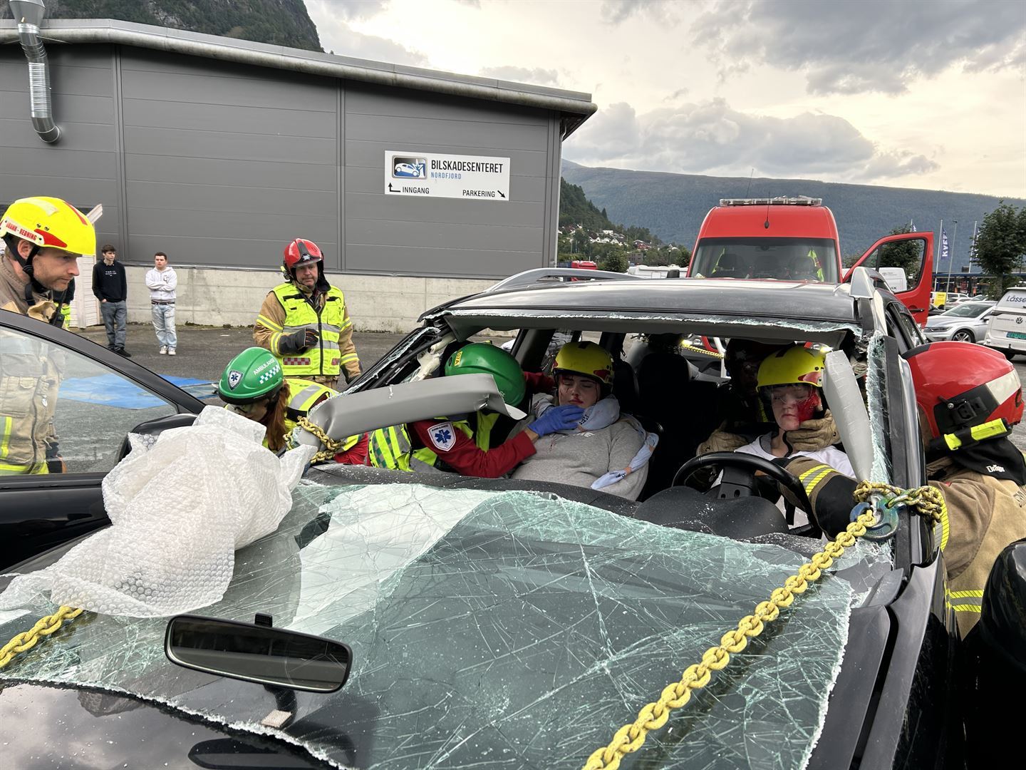 Vi ser inn fronten på ein bil som har kræsja, gjennom knust frontrute. I førarsetet og passasjersetet framme sit det to unge jenter, dei er medvitslause og har maling som skal sjå ut som blod i andleta. Det er tydeleg at det er ein øvingssituasjon. Bilen er omkrinsa av redningsfolk i grå branndressar med gule striper og hjelmar, som jobbar med å sikre bilen og få jentene ut. Ein av mannskapa har hovudet inne i bilen og sjekkar pulsen på halsen til føraren av bilen. Fleire ungdommar ser på øvinga. 