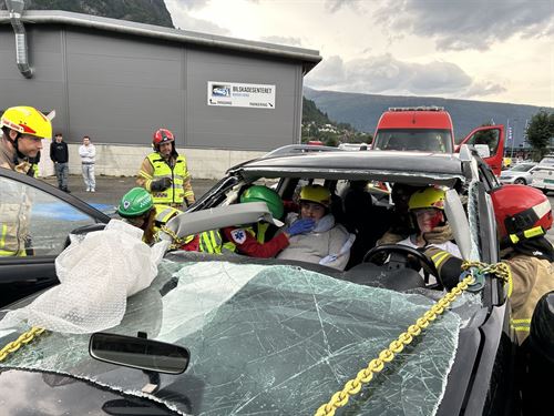 Vi ser inn fronten på ein bil som har kræsja, gjennom knust frontrute. I førarsetet og passasjersetet framme sit det to unge jenter, dei er medvitslause og har maling som skal sjå ut som blod i andleta. Det er tydeleg at det er ein øvingssituasjon. Bilen er omkrinsa av redningsfolk i grå branndressar med gule striper og hjelmar, som jobbar med å sikre bilen og få jentene ut. Ein av mannskapa har hovudet inne i bilen og sjekkar pulsen på halsen til føraren av bilen. Fleire ungdommar ser på øvinga. 