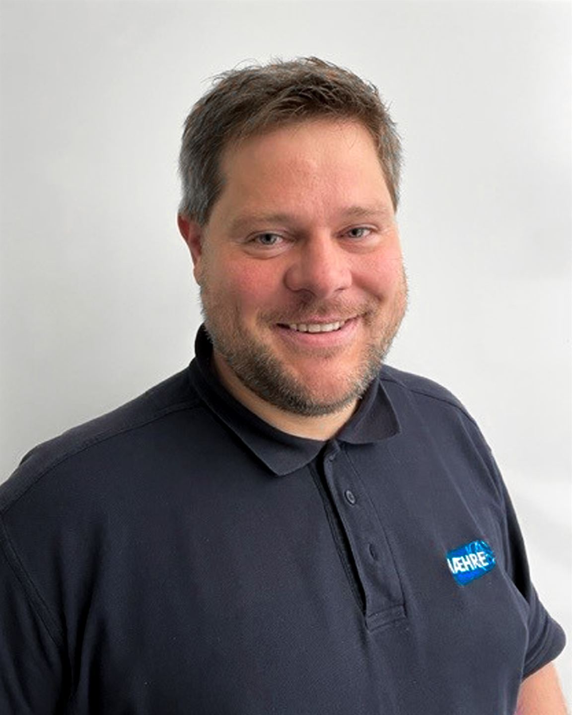 Portrettfoto av mann med blå t-skjorte med krage.