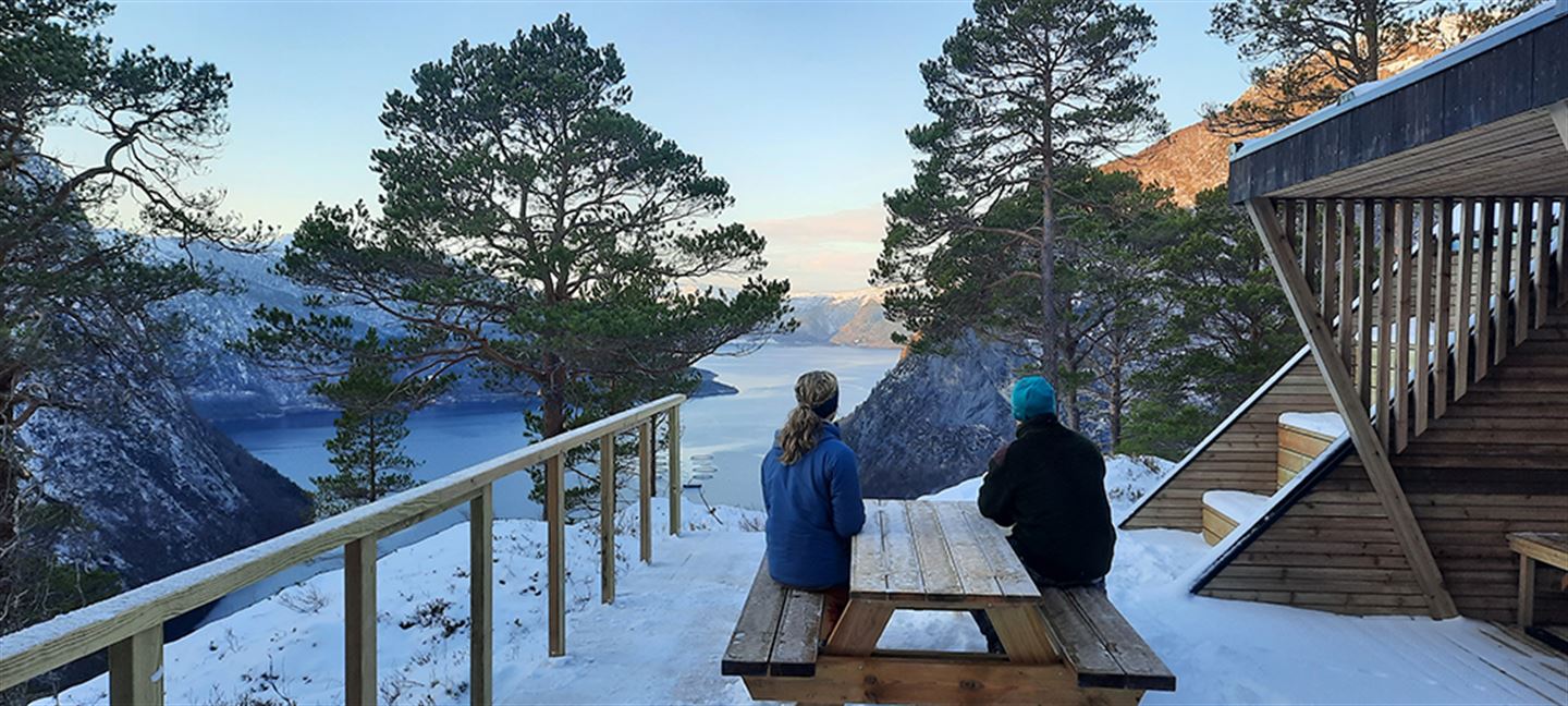 To personar utanfor dagsturhytta Åsenutsikta i Høyanger på vintertid.
