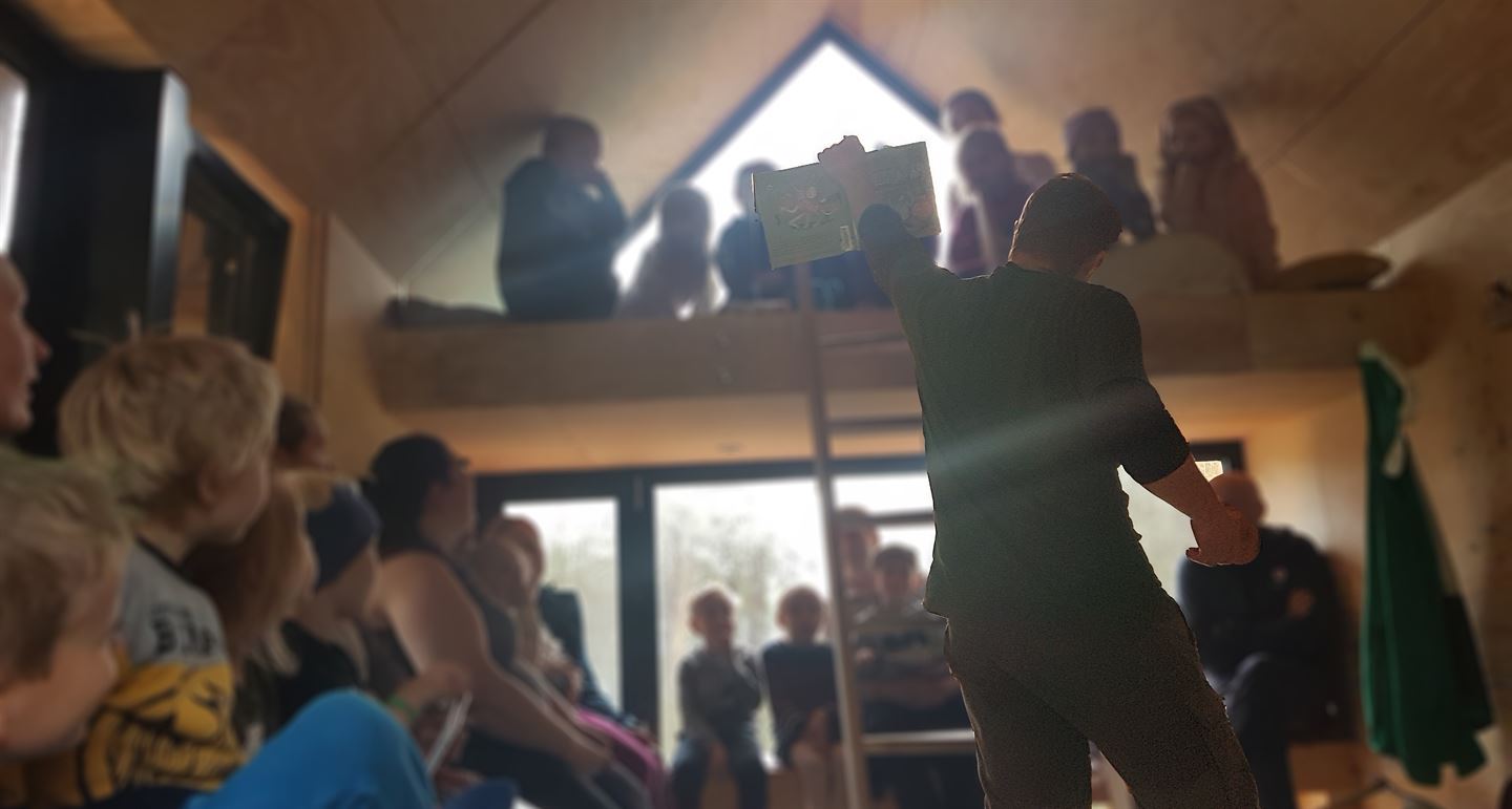 foto av mann som har høgtlesing for barn på ei dagsturhytte