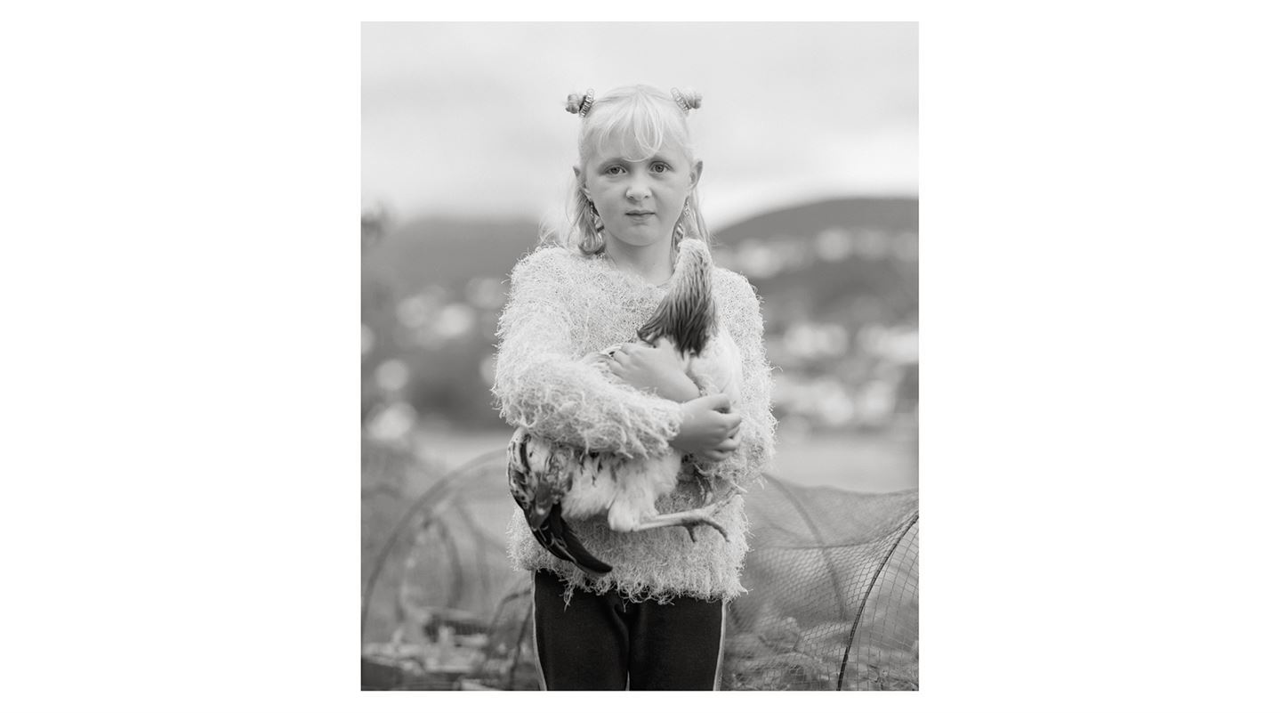 Foto som syner eit fotografi av ei jente som held ei høne.