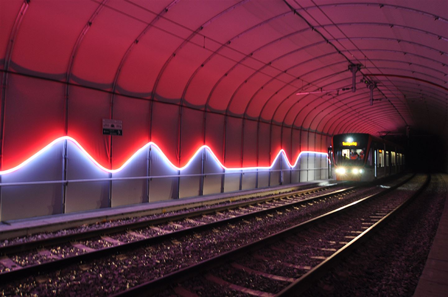 Foto av kunstverket Puls langs bybanetraseen. Det er raudt og blått lys inni ein bybanetunnel.