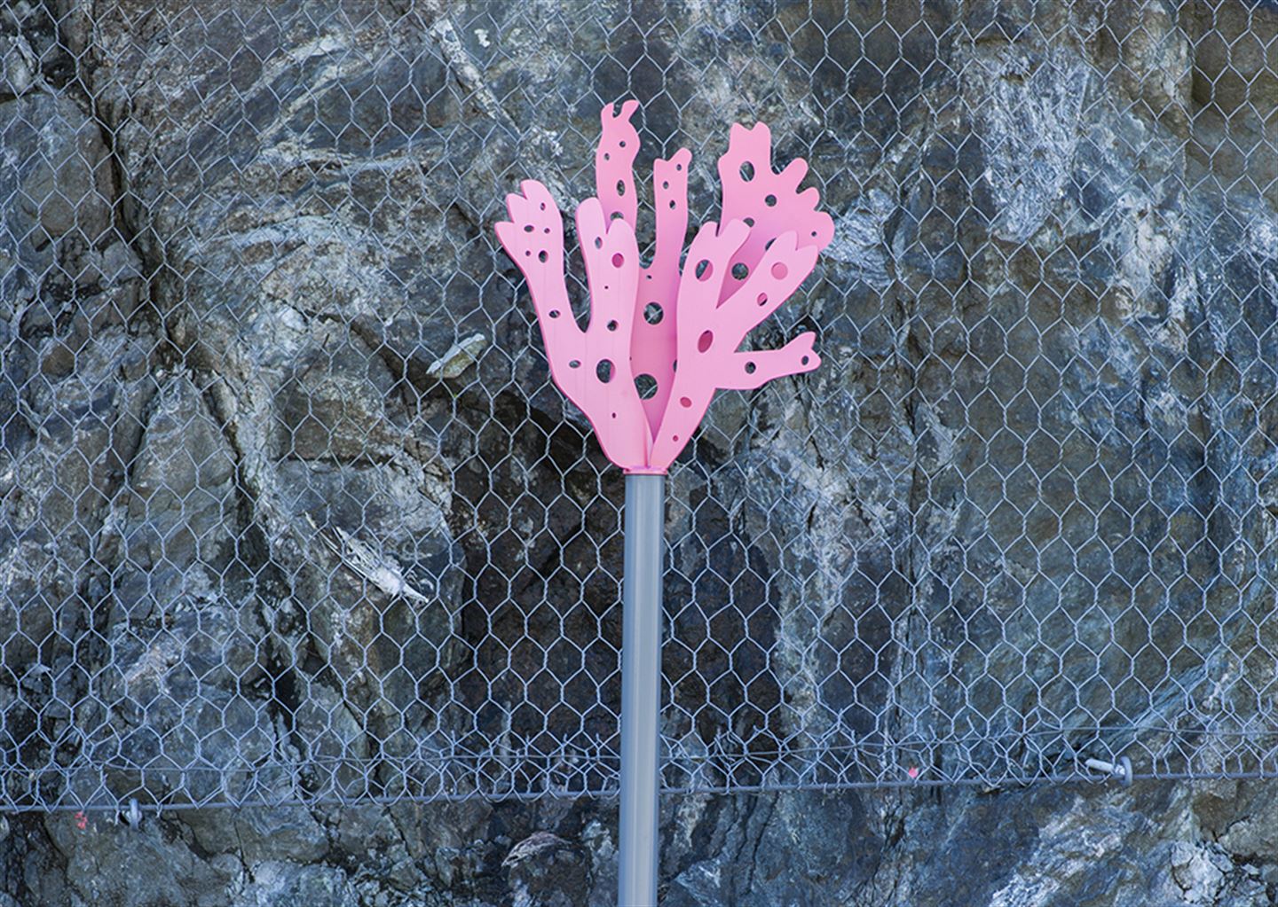 foto av kunstverket Olje-Norge langs bybanetraseen. Det er ein rosa figur festa øvst på ein stolpe.