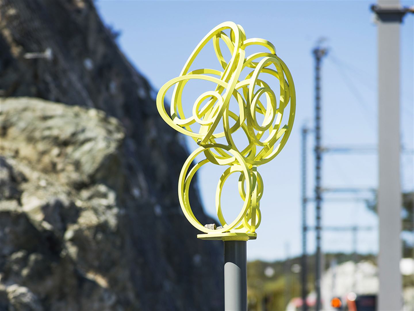 foto av kunstverket Olje-Norge langs bybanetraseen. Det er ein gul figur festa øvst på ein stolpe.