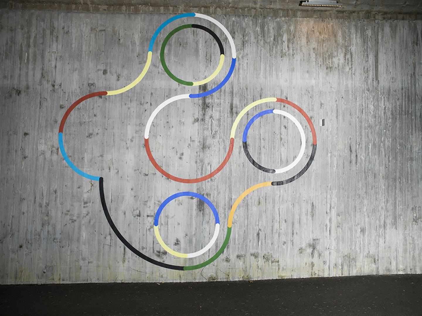 Foto av kunstverket Sirkelspill langs bybanetraseen. Det er fargerike figurar målt på betong.
