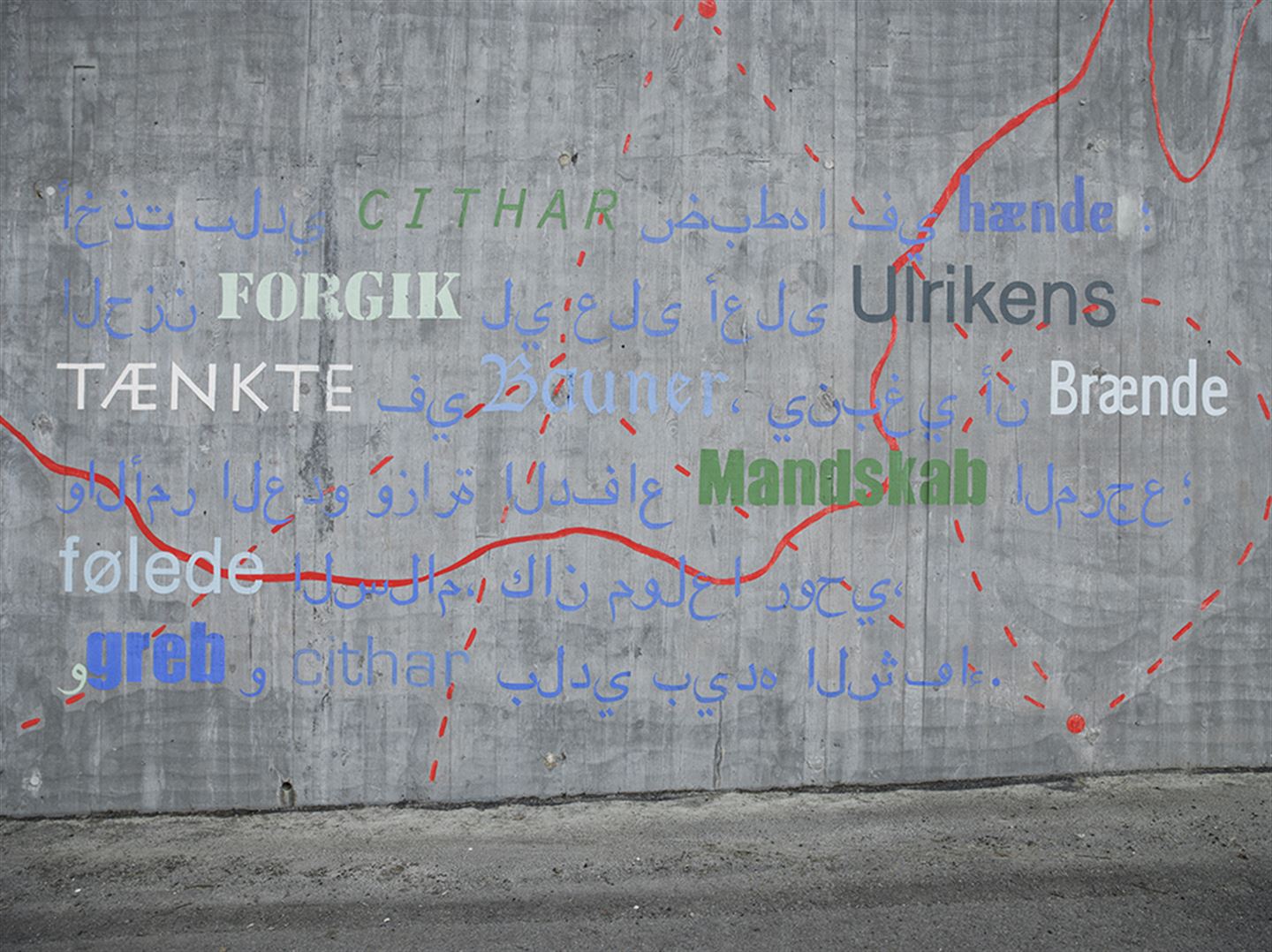 Foto av kunstverket 1: 1 000 483 langs bybanetraseen. Det syner skrift på ein betongvekk, på både norsk og andre språk, i tillegg til raude strekar og prikkar.