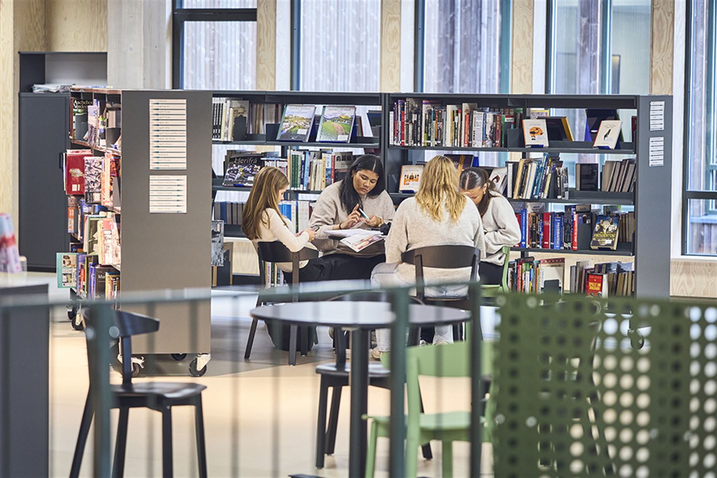 Ungdomar som sit ved eit bord på eit skulebibliotek.