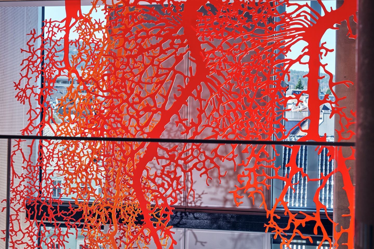 Nærbildet av kunstverk som førestiller oransje røter hengjande frå taket i Vestlandshuset. 