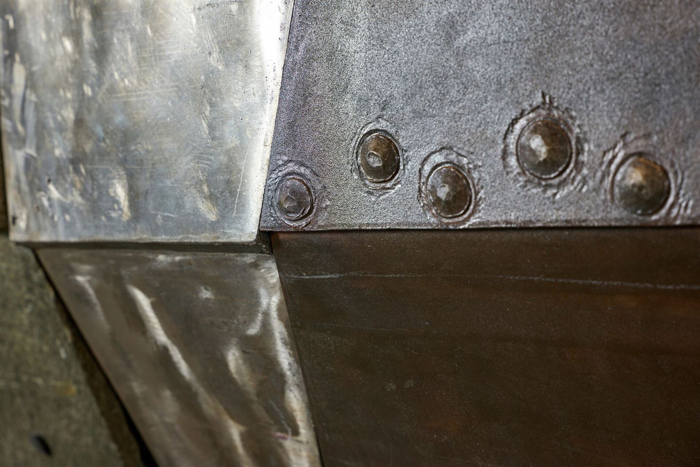 Nærbilde av skifer og rustfritt stål på skulpturen av ein halv båt som heng i resepsjonen på Vestlandshuset.