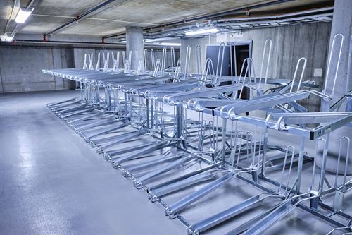 Sykkelstativ på rekke bortover i ein kjellar.