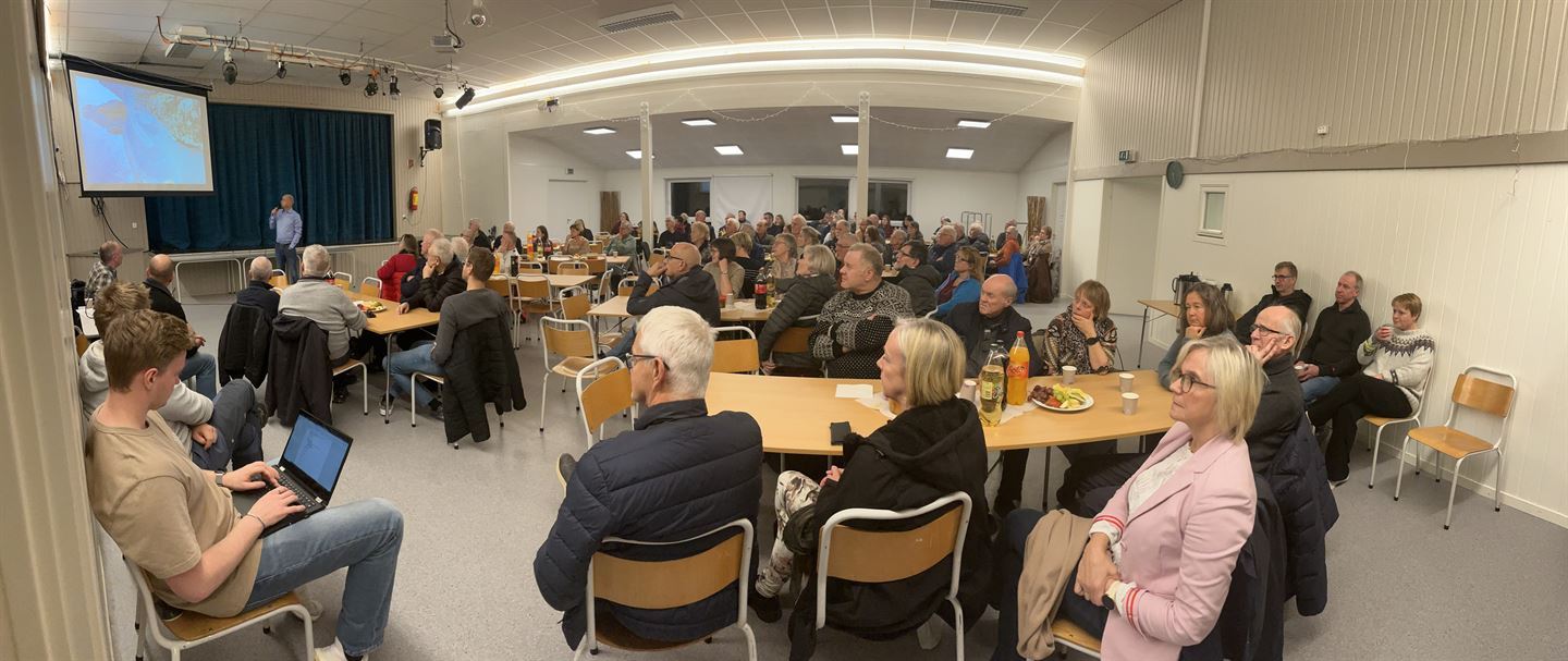Panoramabilde som viser mange menneske i forsamlingsrom. Dei sit rundt bord åtte og åtte, medan ein mann står framme ved scena. Han snakkar mikrofon og viser presentasjon på ein skjerm.