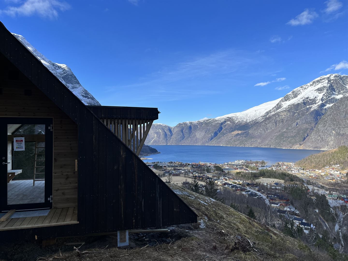 Bilde av ei dagsturhytte med Eidfjord i bakgrunnen.