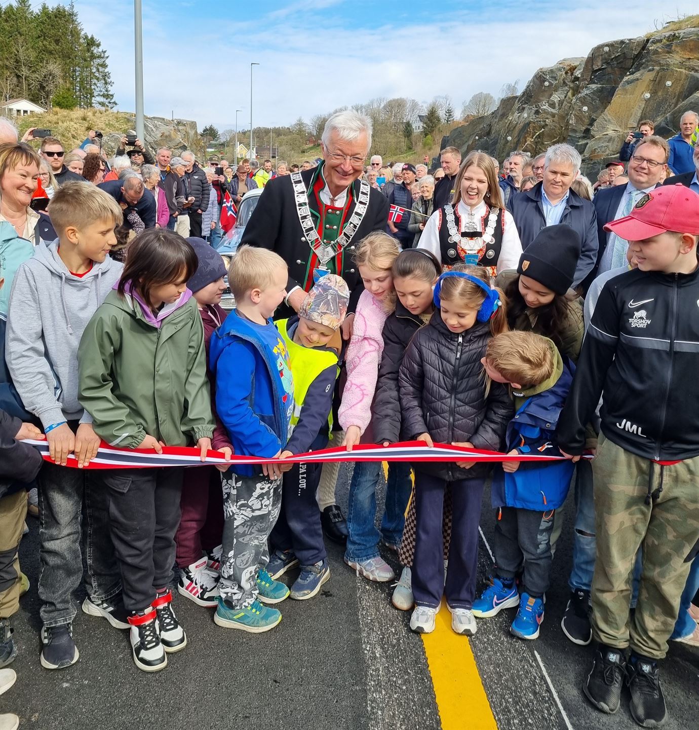 Biletet viser fylkesordførar Jon Askeland, som klipper snoren på opningsmarkeringa saman med skuleborn. 