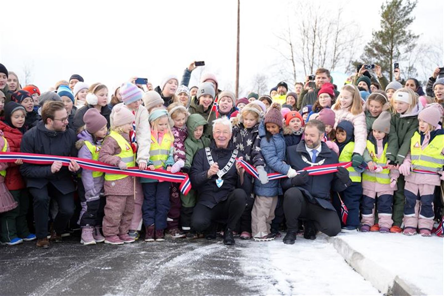 Mange glade folk som står samla foran ein klypt snor.