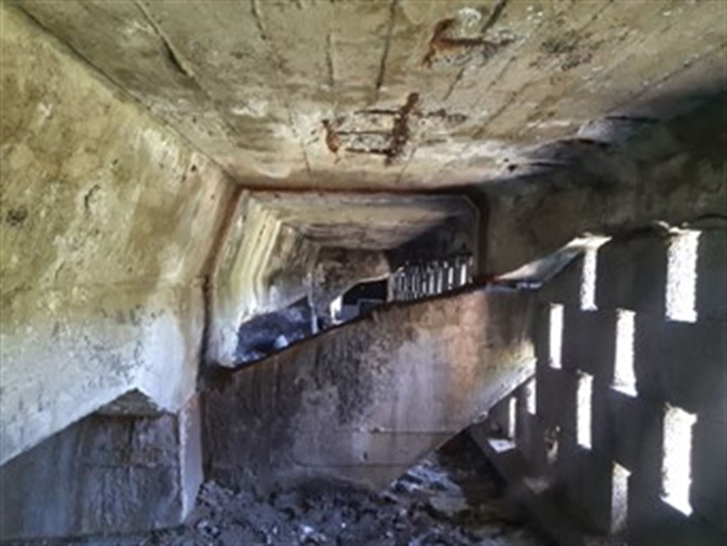 Eit delvis lukka rom med betongtak- og veggar. Hull i veggane.   