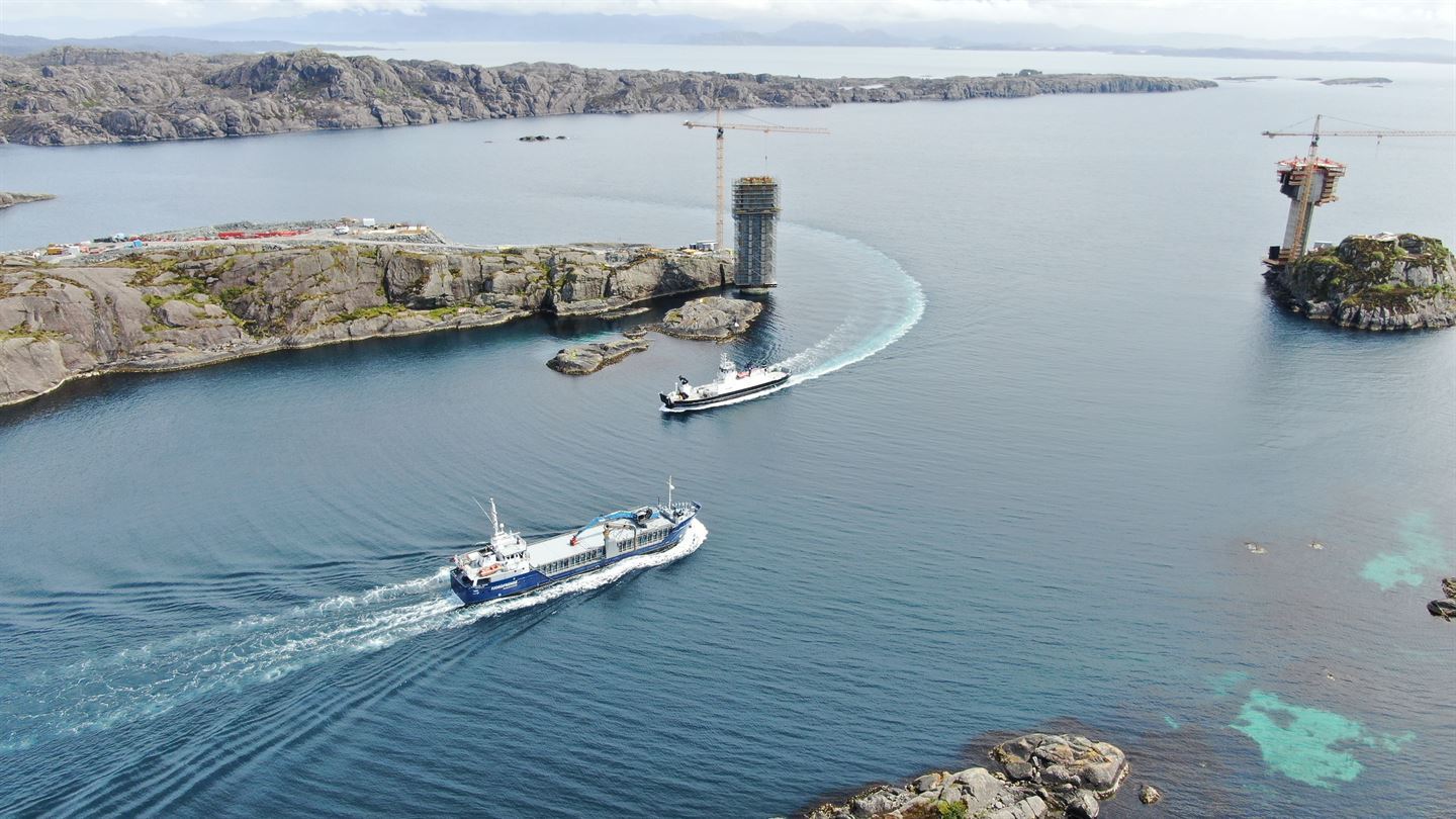 Kystlandskap med sjø og sund, kraner og anleggsarbeid.
