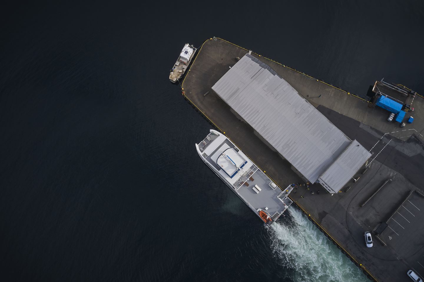 dronebilde sett rett ovenfra av hurtigbåt som ligg til kai.