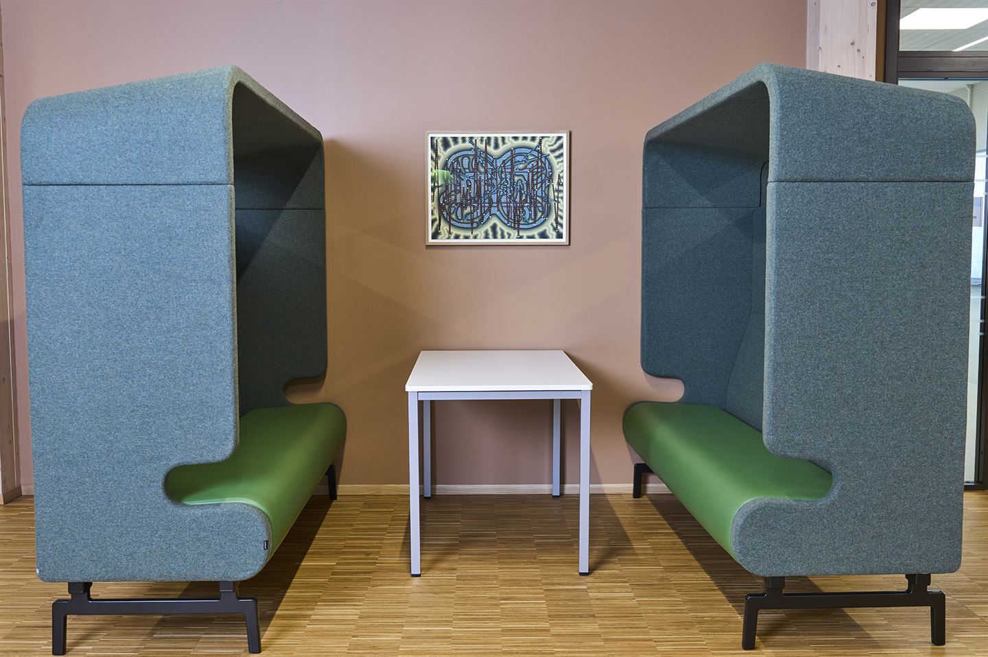 Sittegruppe med to høge sofaar på Stord vgs., med kunstverk av Andreas Lærum på veggen mellom.