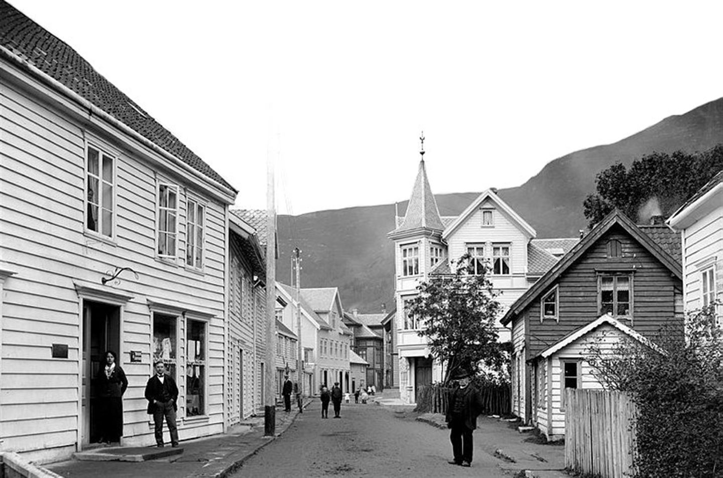 Eit historisk bilete av Eidsgata i Stad kommune, med fleire menn i dress langs gata.